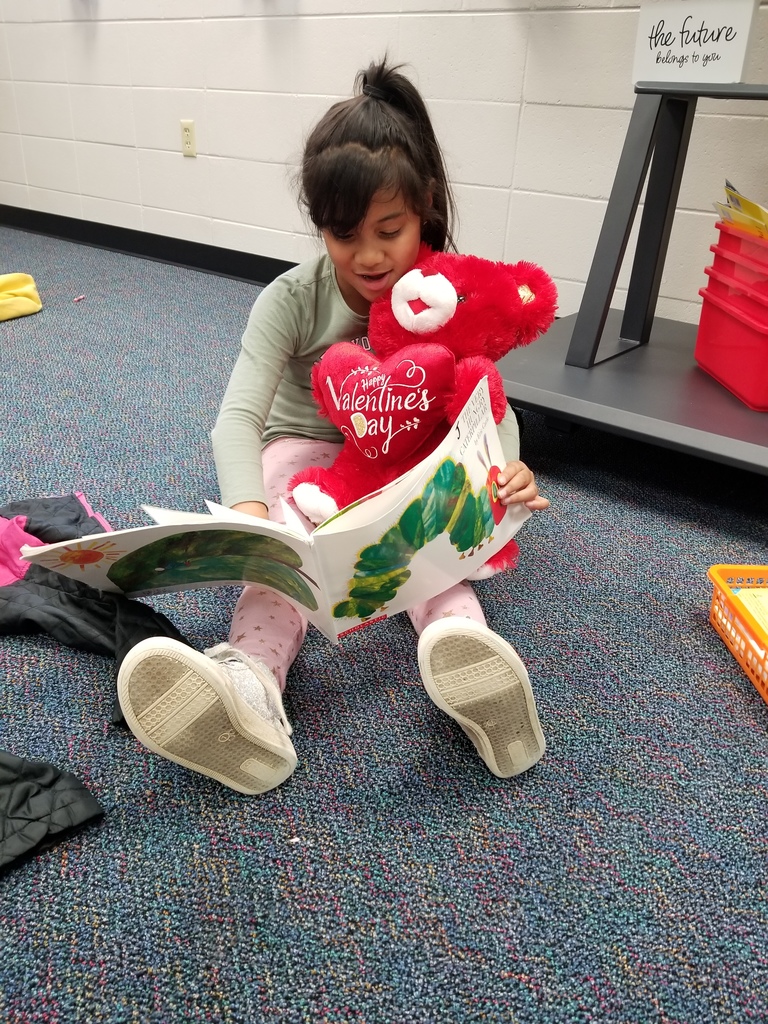 Student reading to stuffed animal. 